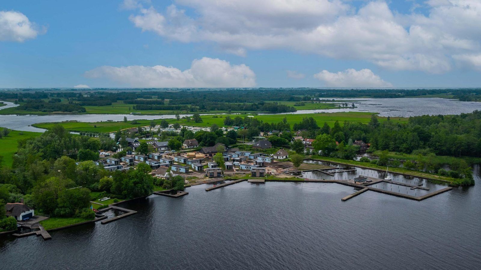 An aerial view of a lakeside village with houses, docks, and a river.
