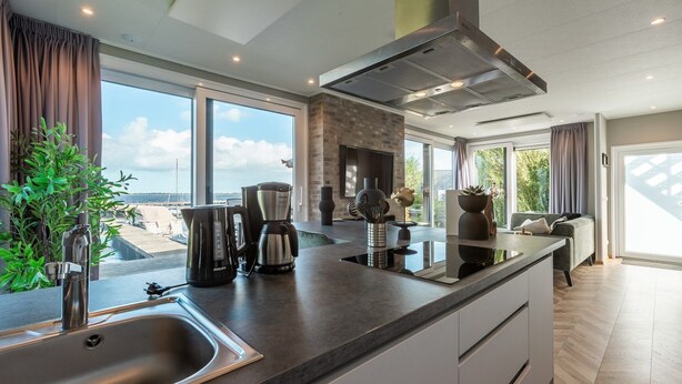A modern kitchen with a large window, a built-in stove, and a sink.