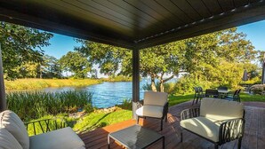 A covered outdoor seating area with a view of a lake and trees.