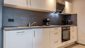 A modern kitchen with white cabinets, a built-in oven, and a coffee maker. - Vacation apartment Anna at the gateway to the Eifel National Park (Heimbach/Eifel) (Heimbach)