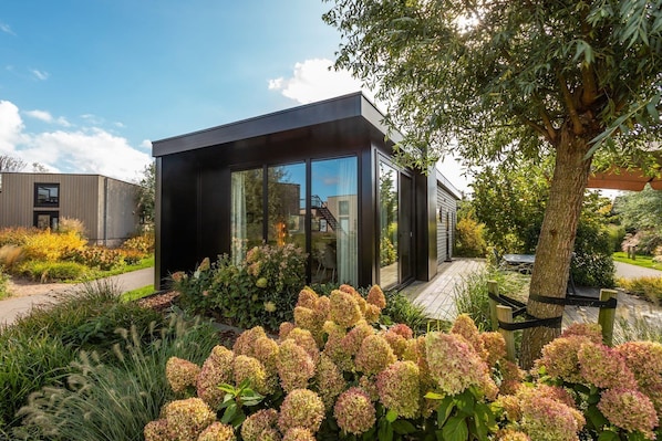 A modern house with a glass facade, surrounded by a garden with hydrangeas.
