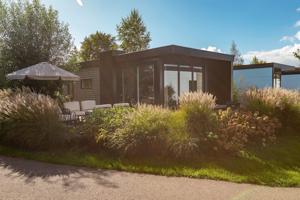 A modern house with a patio, outdoor seating, and a covered area.