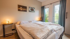 Un dormitorio con una cama, mesitas de noche y dos cuadros colgados en la pared.