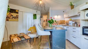 Una cucina moderna con isola in marmo, sgabelli da bar, lampadario e un quadro appeso al muro.