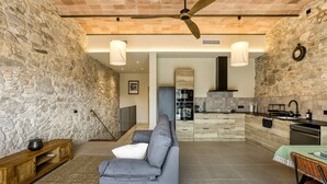A modern kitchen with a stone wall, a wooden bench, and a gray sofa.