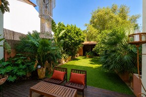 A patio with wooden furniture, a small lawn, and various potted plants. - Villa in Porto with private garden (Porto)