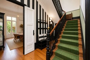 A staircase with green carpeted steps and black balusters, leading to a landing with a wooden bench and a white door. - Villa in Porto with private garden (Porto)