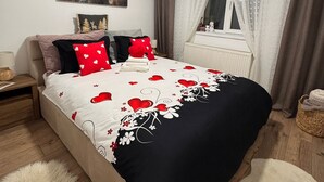Makuuhuone, jossa on sänky, yöpöytä, ikkuna verhoilla, seinälle ripustettu taulu ja patteri.
