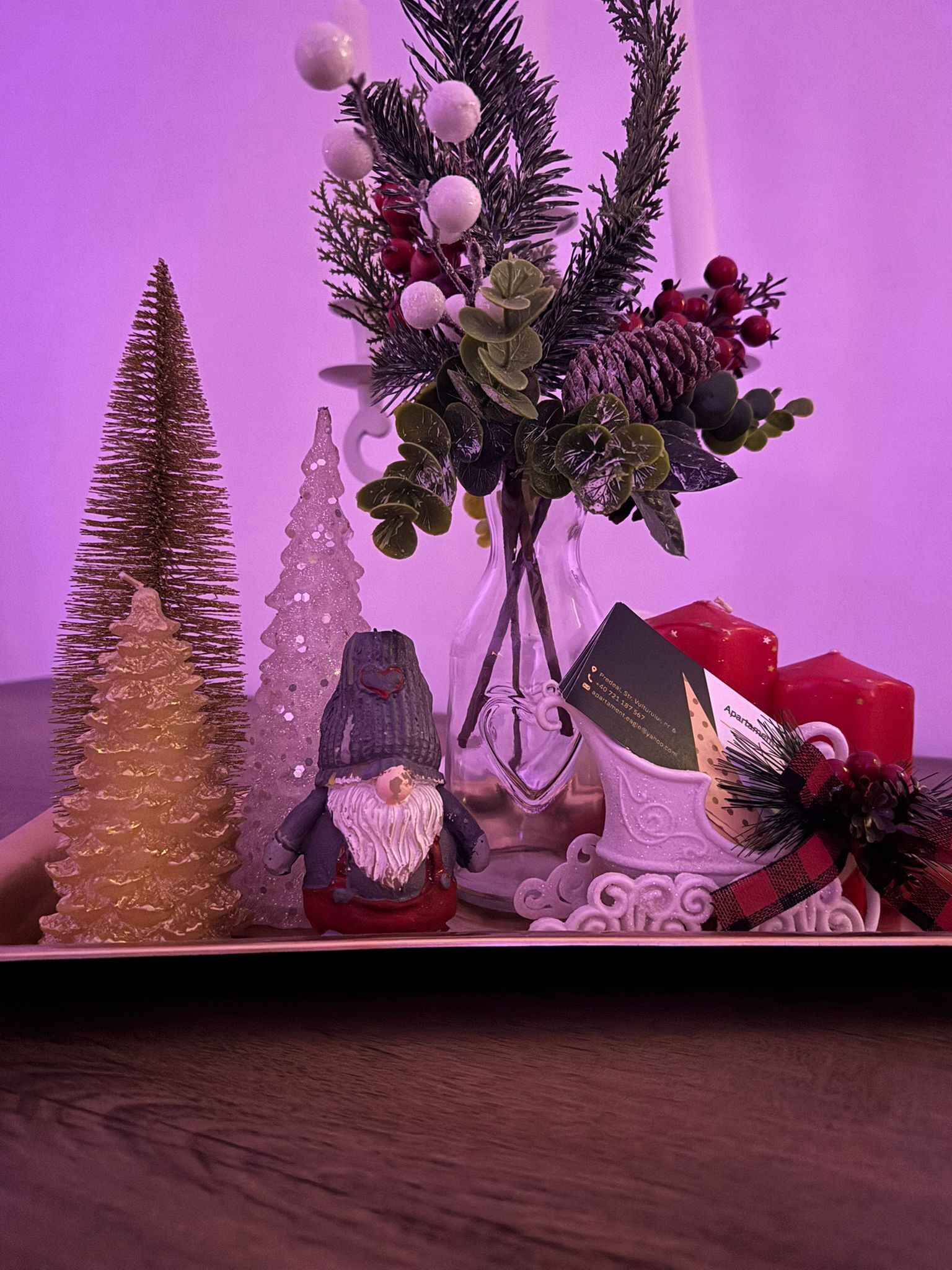 Un sapin de Noël, un gnome, un vase avec des décorations végétales et une boîte à cadeaux.