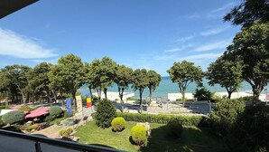 A view from a balcony overlooking a landscaped area with trees and a beach. - Hotel Corsa Managalia (Mangalia)