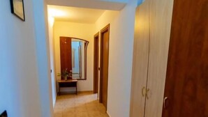A hallway with a tiled floor, wooden doors, and a mirror on the wall. - Hotel Corsa Managalia (Mangalia)