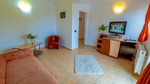 A small living room with a sofa, a red chair, a TV, a small table, and a cabinet. - Hotel Corsa Managalia (Mangalia)