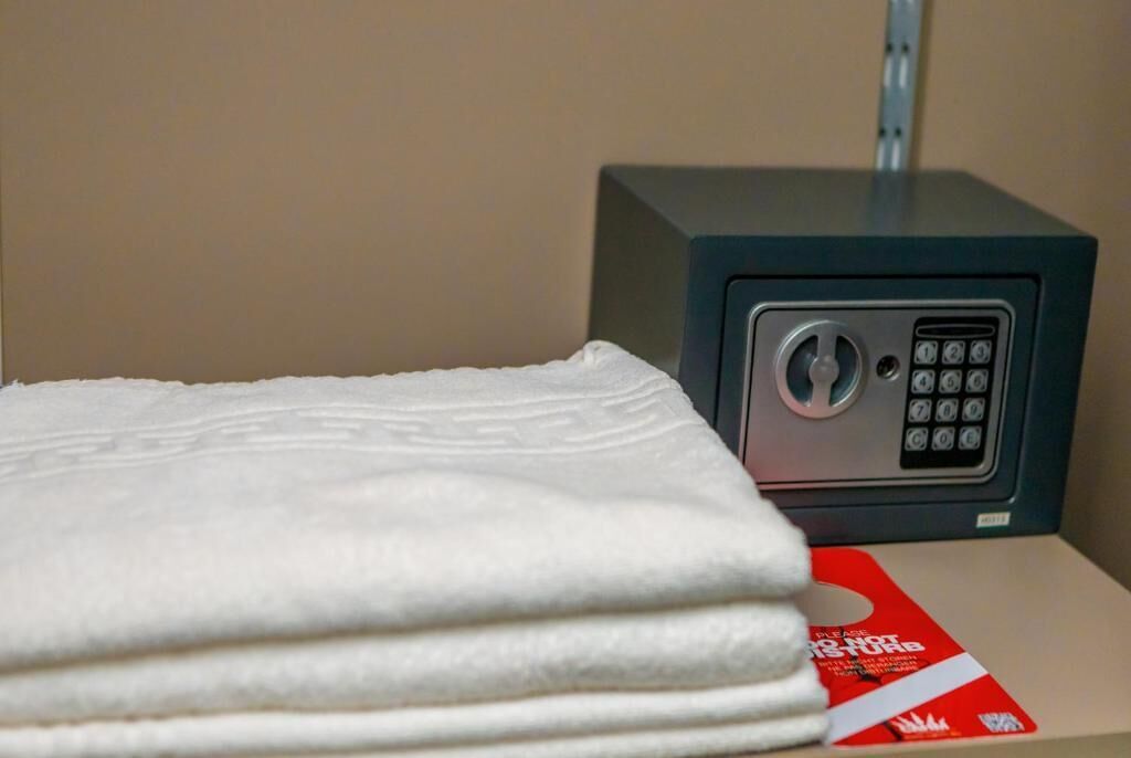 A stack of white towels and a safe with a keypad lock.