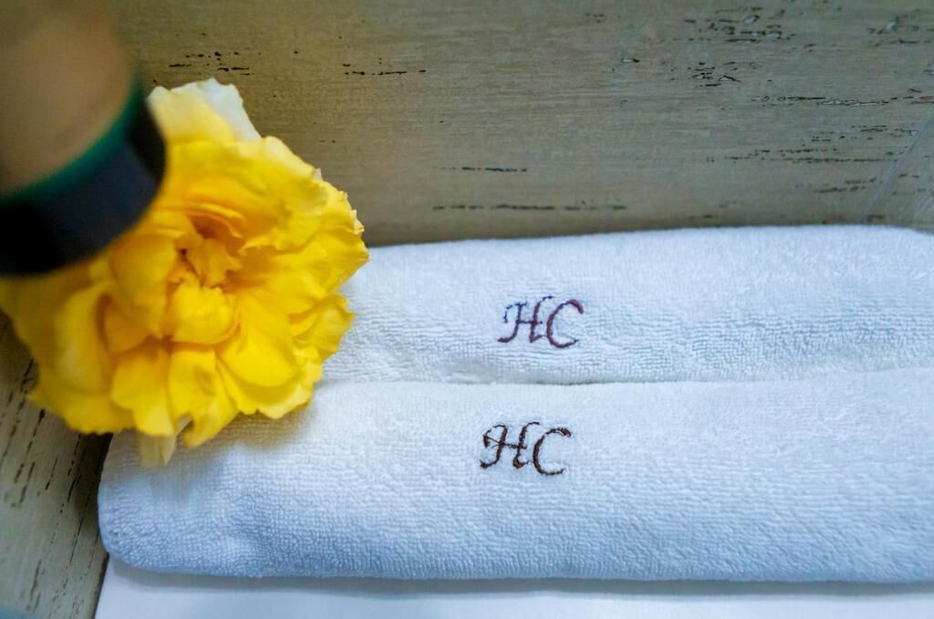 A white towel with embroidered initials 'HC' on a wooden surface.