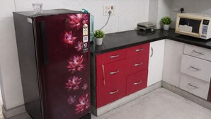Una cocina con refrigerador, microondas y armarios.