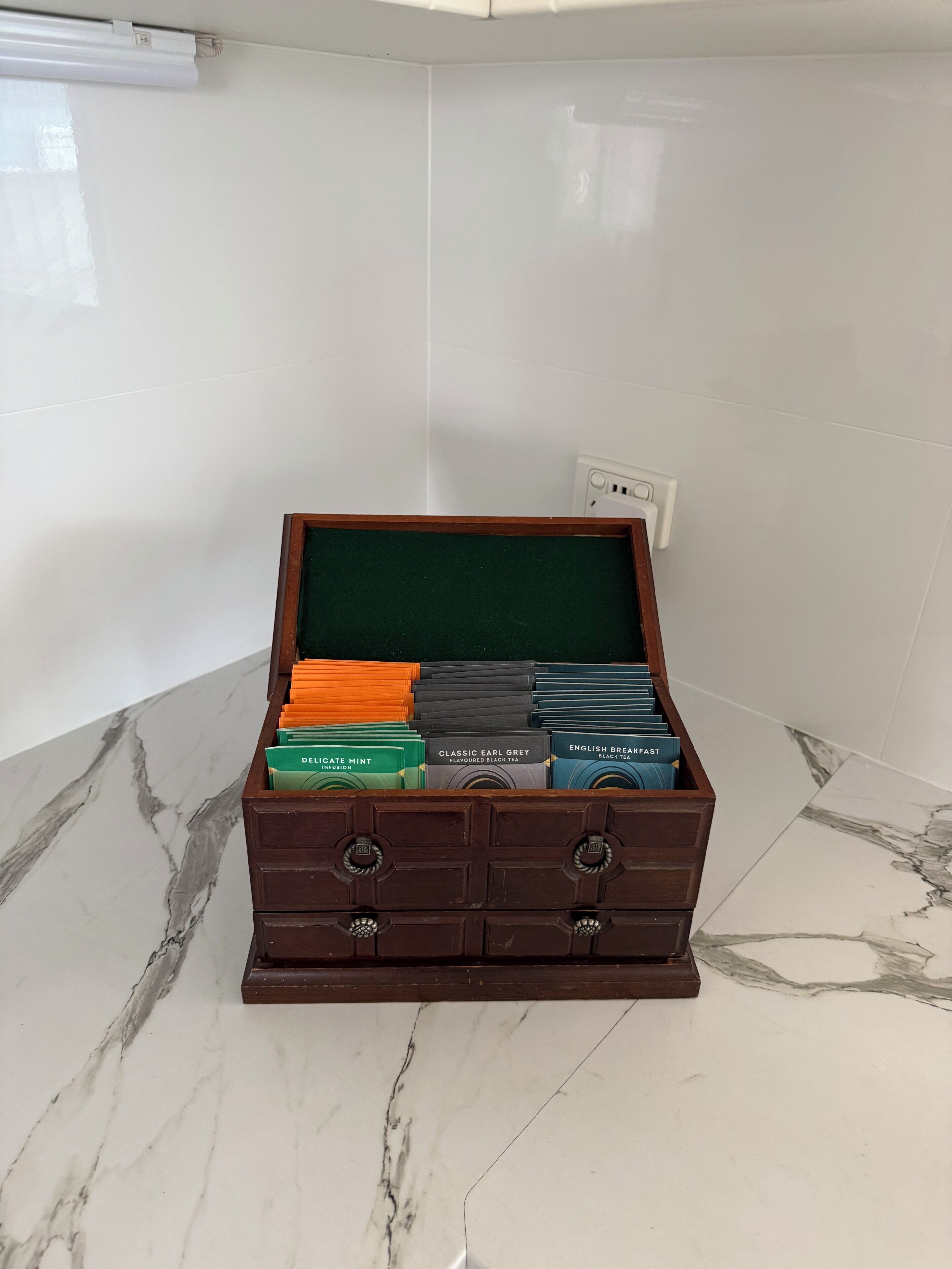 A wooden chest with compartments containing various tea boxes.