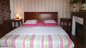 Una cama bien hecha con colcha a rayas, un cabecero de madera y dos mesitas de noche con lámparas.