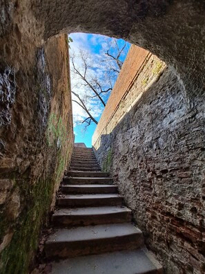 Una escalera de piedra que sube por un estrecho pasaje, con un cielo azul despejado visible arriba.