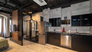 Una cocina moderna con lavavajillas integrado, refrigerador y cabina de ducha de vidrio.
