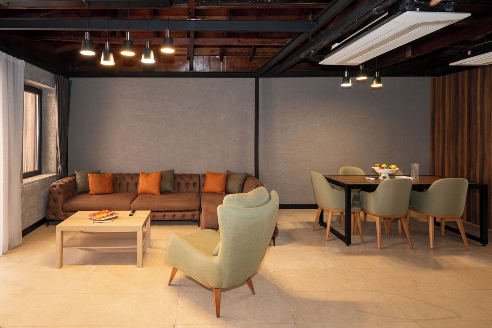 A modern living room with a sofa, armchair, coffee table, and dining area with chairs and a table.