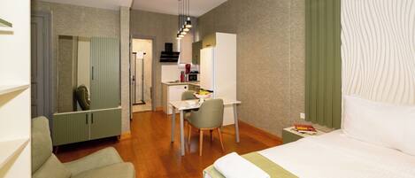 A hotel room with a bed, a desk, a chair, and a kitchenette.