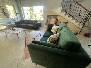 Ein Wohnzimmer mit einem grünen Sofa, einem grauen Couche und einem Couchtisch.