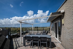 Une terrasse extérieure dotée d’une pergola, de sièges et offrant une vue sur le paysage.