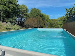 A clear swimming pool surrounded by trees and a wall. - Private property, two houses, gym, pool and outside bar in stunning surrounding (Bosia Cuneo)