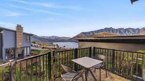 A balcony with a table and chairs, overlooking a lake and mountains. - Alpine 75 Cottage - Queenstown Hill 2 Bed (Queenstown)