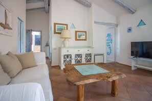 A living room with a sofa, a wooden coffee table, a TV, and a cabinet with glass doors. - Cozy and bright 80 square meters apartment, perfect for four people, located on the first floor of a condominium with a swimming pool (no elevator).The property is located in Liscia di Vacca, a short distance from Porto Cervo, reachable by car or public  (Liscia di Vacca)