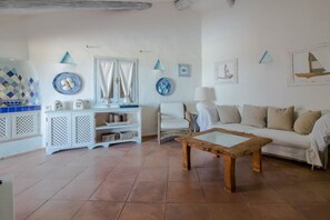 Un salon avec un canapé blanc, une table basse en bois, un fauteuil blanc, un meuble blanc et des assiettes décoratives accrochées au mur.