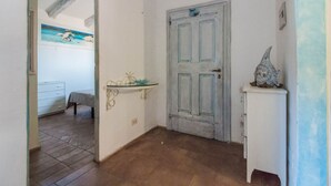A room with a door, a small table, a dresser, and a painting on the wall. - Cozy and bright 80 square meters apartment, perfect for four people, located on the first floor of a condominium with a swimming pool (no elevator).The property is located in Liscia di Vacca, a short distance from Porto Cervo, reachable by car or public  (Liscia di Vacca)