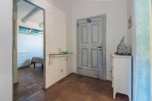 Ein Zimmer mit Tür, einem kleinen Tisch, einem Schminktisch und einem Bild an der Wand.