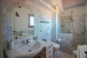 A bathroom with a large sink, a mirror, a shower, and a toilet. - Cozy and bright 80 square meters apartment, perfect for four people, located on the first floor of a condominium with a swimming pool (no elevator).The property is located in Liscia di Vacca, a short distance from Porto Cervo, reachable by car or public  (Liscia di Vacca)