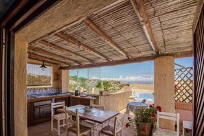Eine Außenküche mit Blick, Holzmöbel und eine Pergola.
