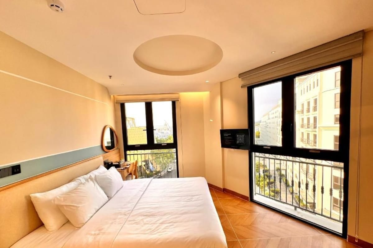 Ein Hotelzimmer mit einem großen Bett, einem Balkon mit Blick und einem Fernseher.