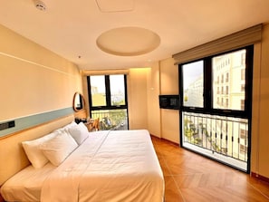 Ein Hotelzimmer mit einem großen Bett, einem Balkon mit Blick und einem Fernseher.