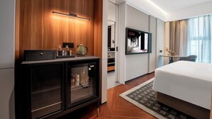 A hotel room with a bed, a TV, a minibar, and a wooden accent wall. - ZhongShan InterCity Expo Center Hotel (Zhongshan)