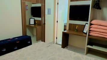Un dormitorio con cama, armario y escritorio con silla.