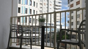 A balcony with a table and chairs, a potted plant, and a view of multi-story buildings. - Cosmos Luxury Studio Suites (Tirana)