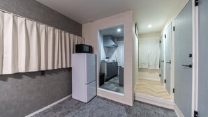 Una habitación compacta con kitchenette, armario y espejo.