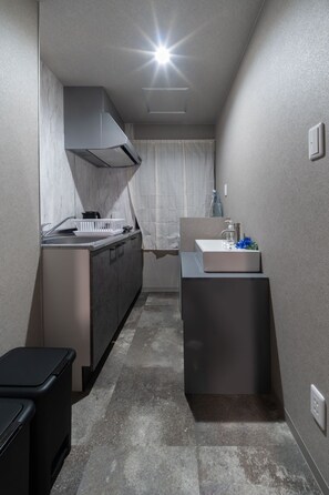 A narrow kitchen with a built-in stove, a small sink, and a compact countertop. - Oyado Kinokuniya Ekimaemachi (Nagasaki city)