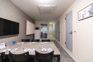 A conference room with a long table, chairs, a flat-screen TV, and a ceiling-mounted air conditioner. - Oyado Kinokuniya Ekimaemachi (Nagasaki city)