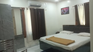 Ein Hotelzimmer mit Bett, Nachttisch, Spiegel, Klimaanlage und einem Bild an der Wand.