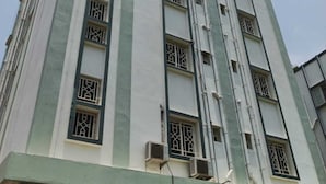 Ein mehrstöckiges Gebäude mit einer symmetrischen Fassade, vertikalen Linien und gleichmäßig verteilten Fenstern.