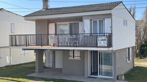 Ein zweistöckiges Wohngebäude mit Balkon, Garagentor und Schild, das auf Mietangebote hinweist.