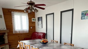 Ein Essbereich mit Tisch, Stühlen, Deckenventilator, Kamin und einer Tür.