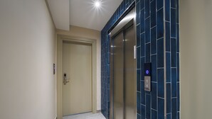 A hallway with a closed door, a blue-tiled elevator, and a light fixture on the ceiling. - Stern Hotel Karaköy (İstanbul)