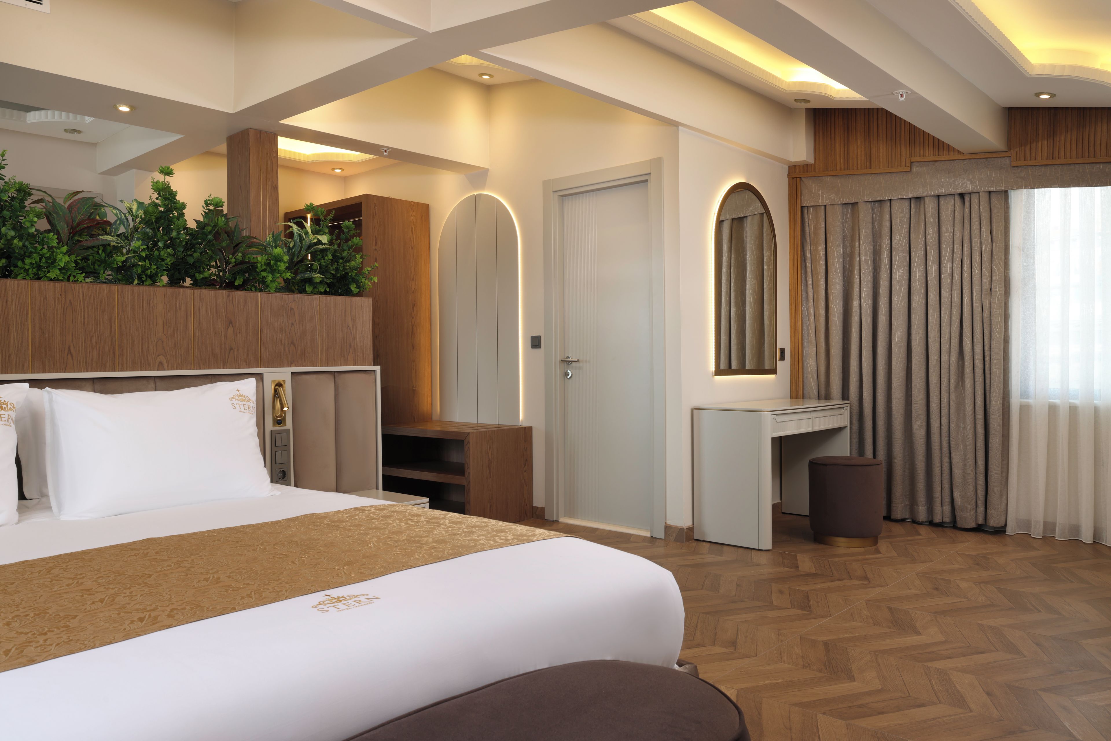 Une chambre d’hôtel avec un grand lit, un bureau, un miroir et une armoire.