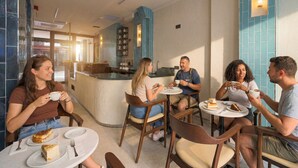 A café with round tables and chairs, a central counter, and a tiled wall. - Stern Hotel Karaköy (İstanbul)